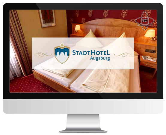 Auf einem Computerbildschirm ist ein Hotelzimmer des Stadthotels Augsburg zu sehen.